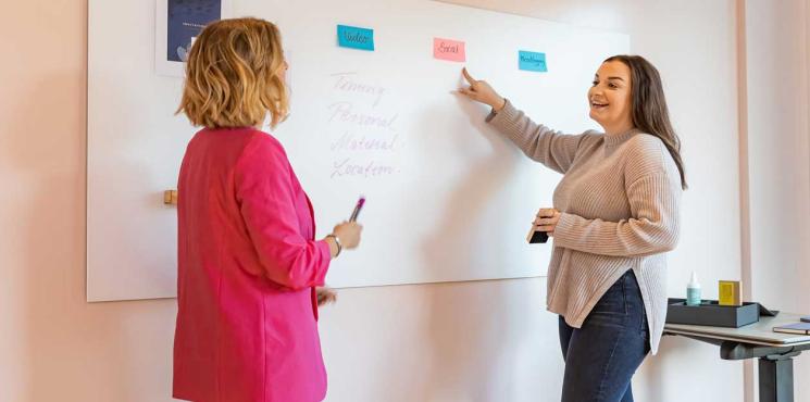 Zwei Kolleginnen tauschen sich an Whiteboard aus